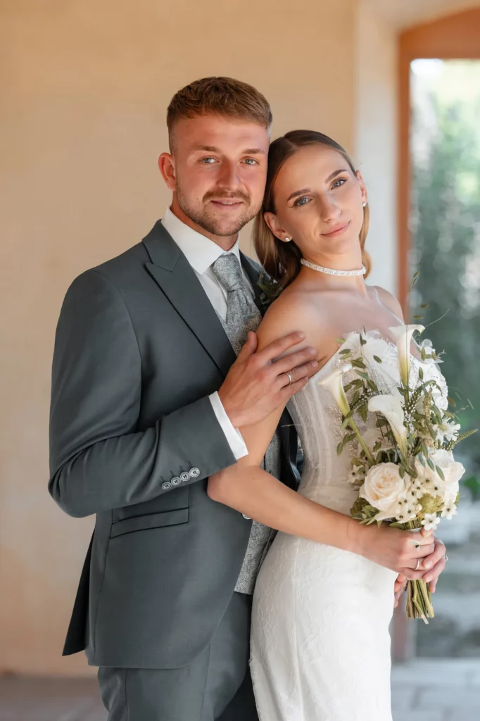 Brautpaar umarmt sich mit Brautstrauß