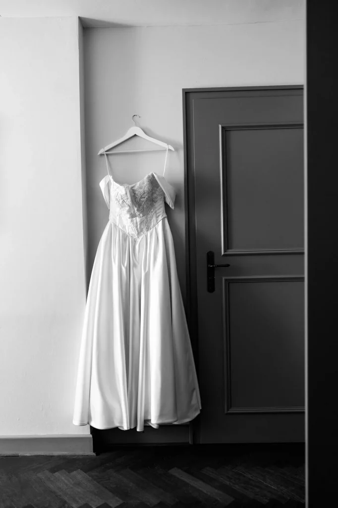 Weißes Brautkleid hängt an Wand neben Tür