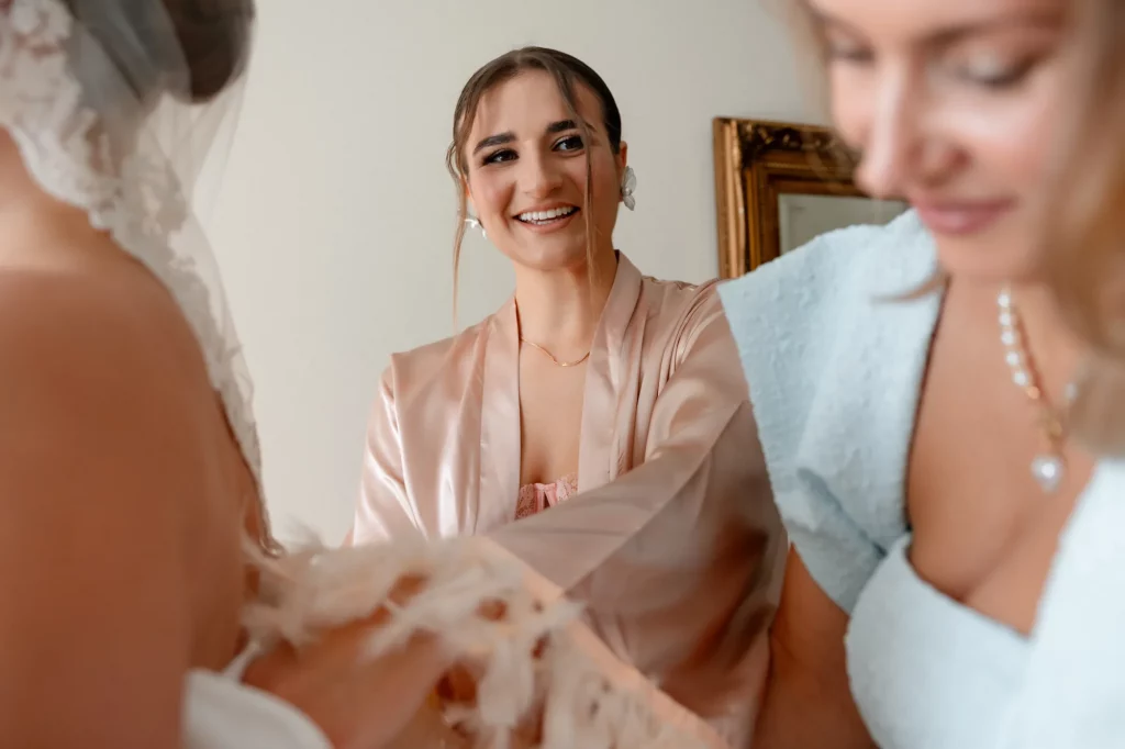 Frau lächelt während Brautkleid angezogen wird