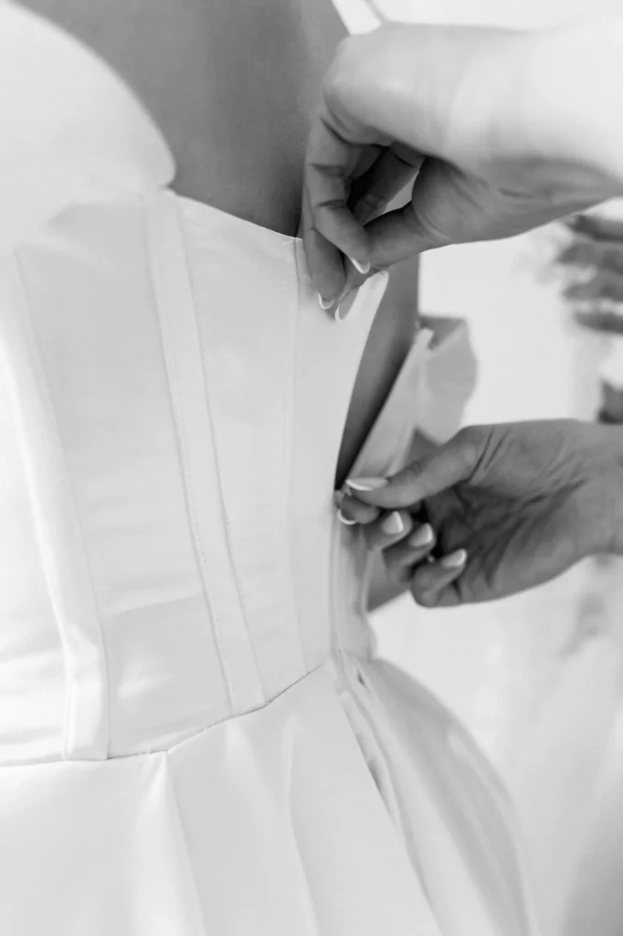 Hände schließen den Rücken vom Brautkleid