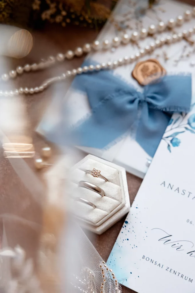 Eheringe in Box mit blauer Schleife und Einladung