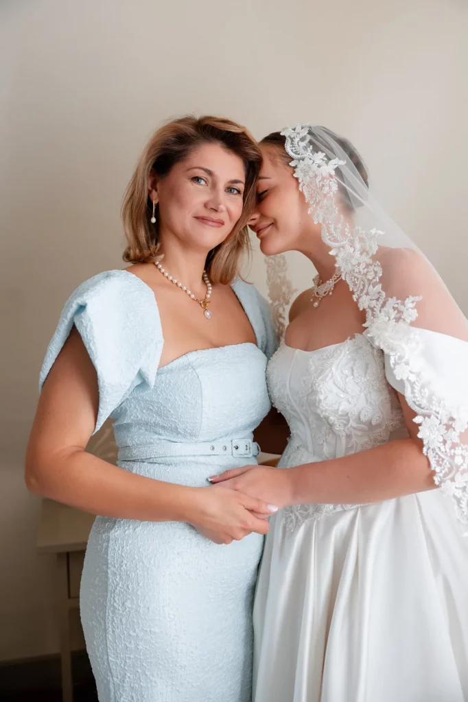 Braut lehnt sich an Mutter mit blauem Kleid