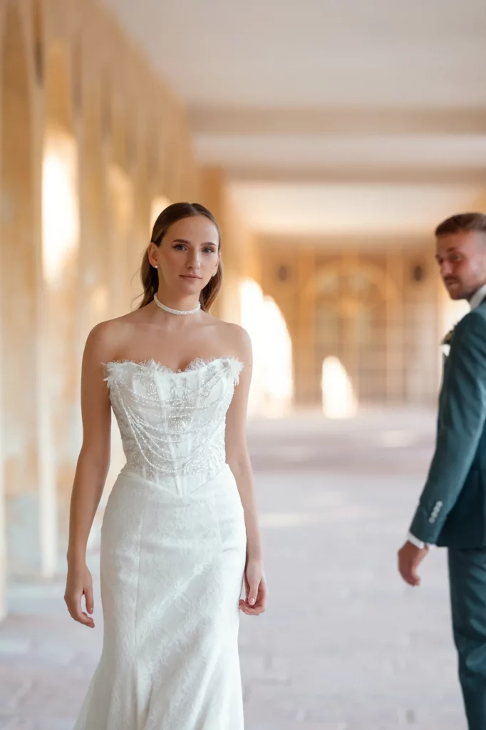 Braut im weißen Kleid vor hellem Gang