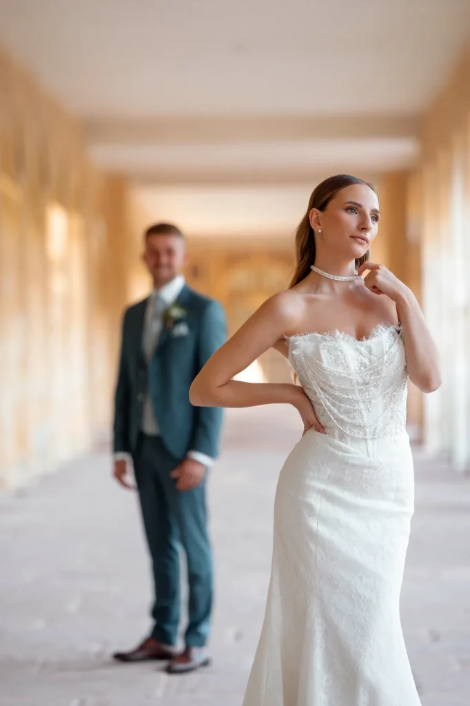 Braut im weißen Kleid mit Bräutigam im Hintergrund