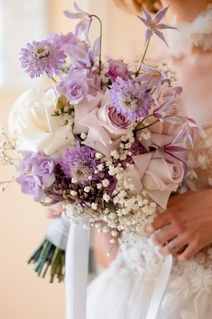 Braut hält lila und weiße Blumen