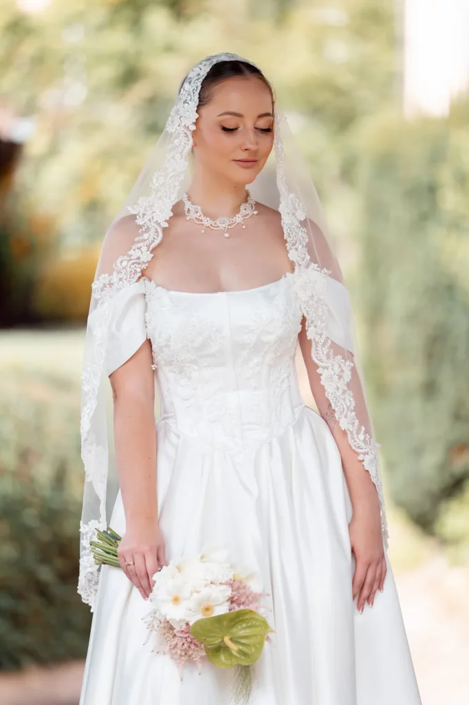 Braut mit Spitzen-Schleier und Blumenstrauß