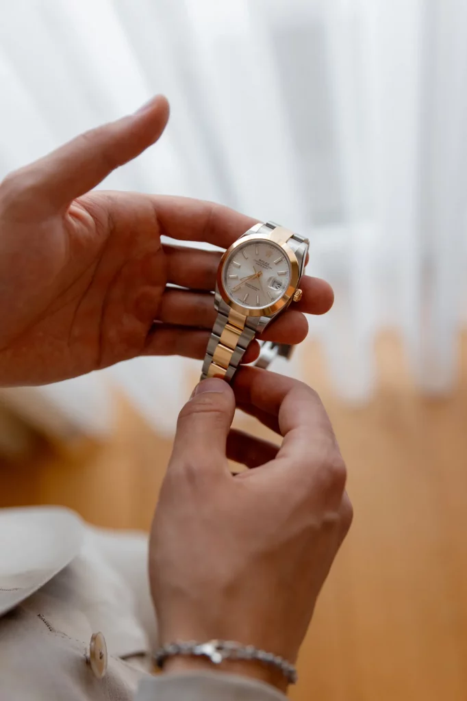 Hände halten gold-silberne Armbanduhr