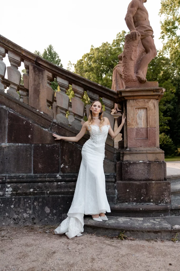 Braut in weißem Kleid an steinerner Treppe