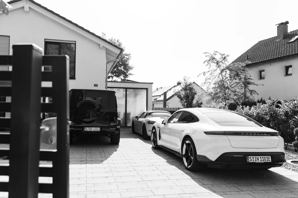 Brautpaar steht vor Haus mit Autos