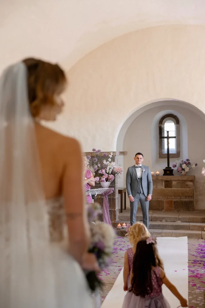 Braut mit Blumenstrauß und Blumenmädchen vor Altar