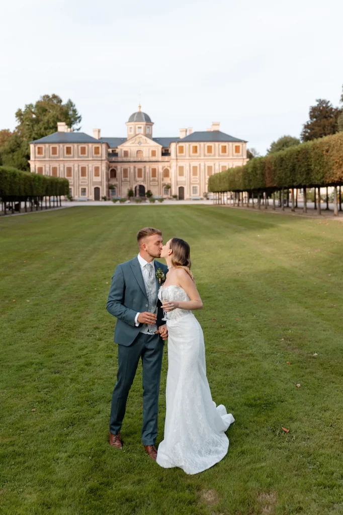 Brautpaar küsst sich auf Rasen vor Schloss