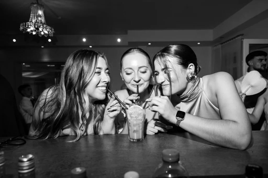 Drei Frauen trinken gemeinsam aus einem Glas