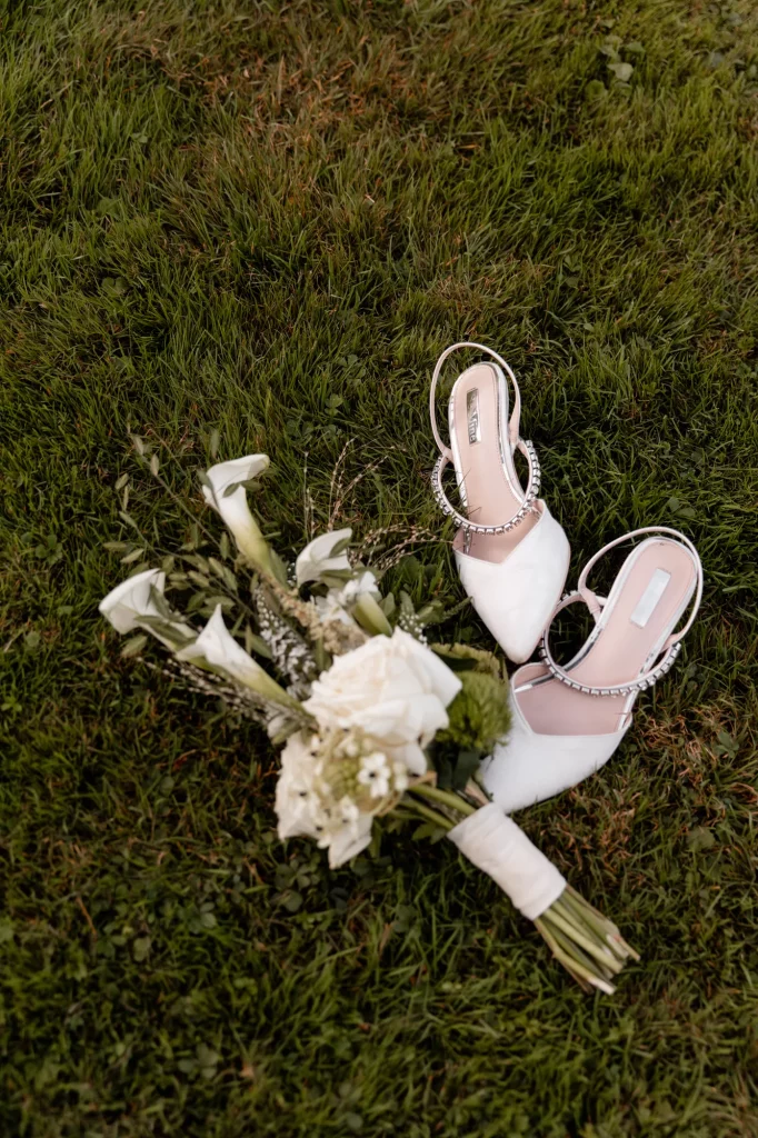 Weiße Brautschuhe und Blumenstrauß auf Gras