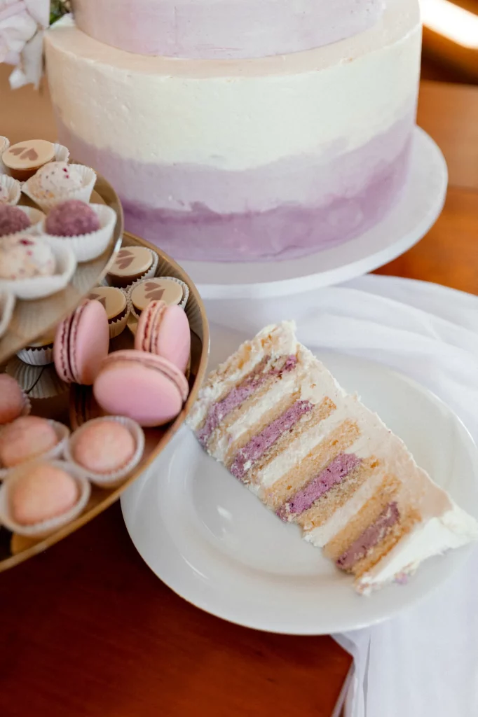 Stück Hochzeitstorte und Macarons auf Tisch
