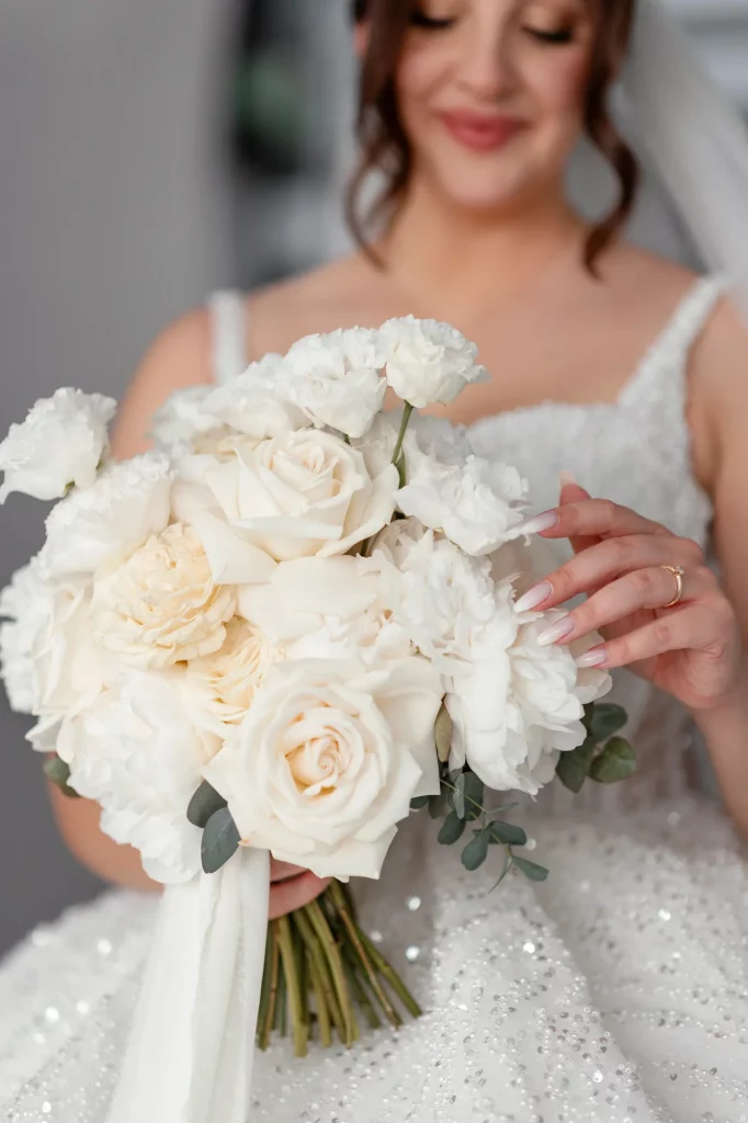 Braut hält weißen Blumenstrauß mit Rosen