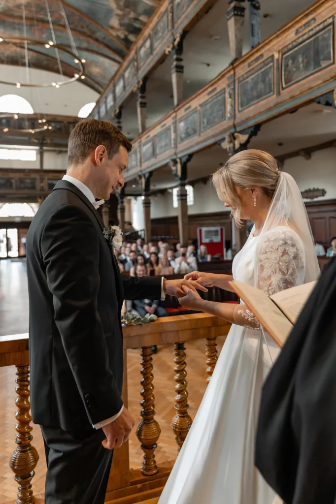 the bride places a ring on the groom during the wedding ceremony in the church