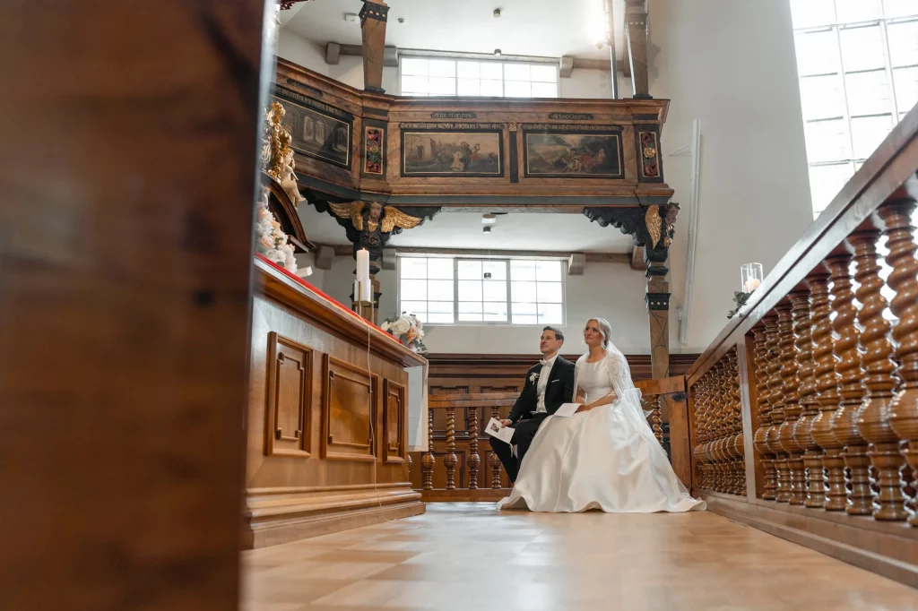 the groom and the bride sit in the church during the wedding ceremony