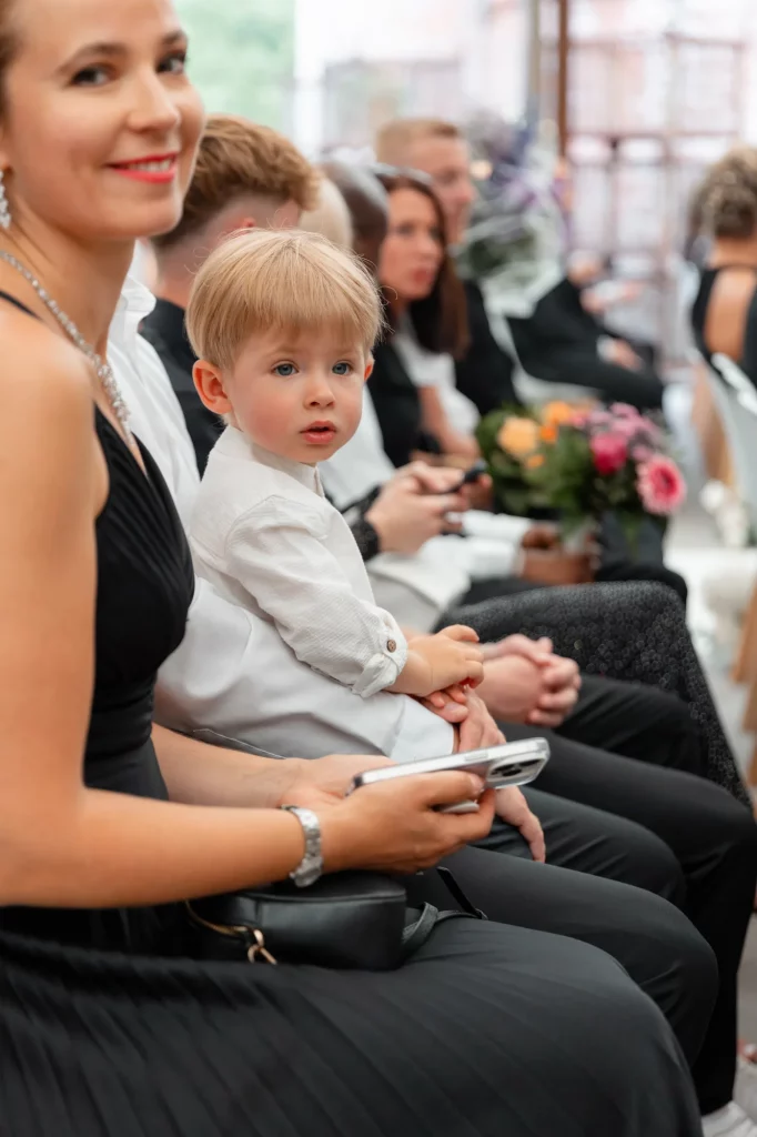 Kind sitzt bei Hochzeit zwischen Gästen