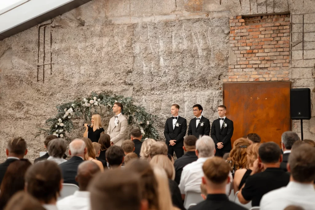 Brautpaar und Trauzeugen vor rustikaler Wand