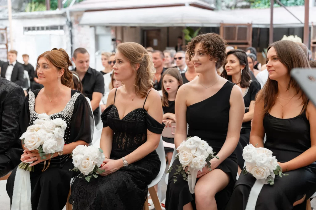 Vier Frauen in schwarzen Kleidern mit Brautsträußen