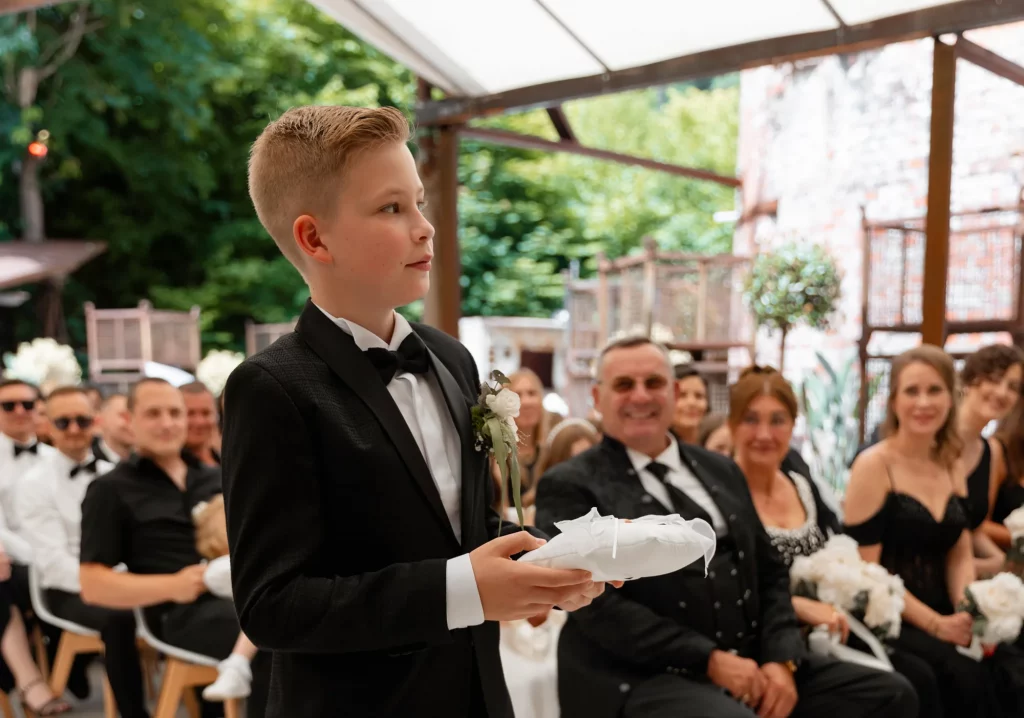 Junge im Anzug hält Ringkissen bei Hochzeit
