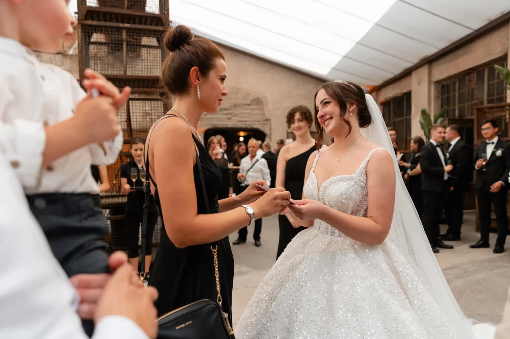 Braut im weißen Kleid spricht mit Frau im schwarzen Kleid
