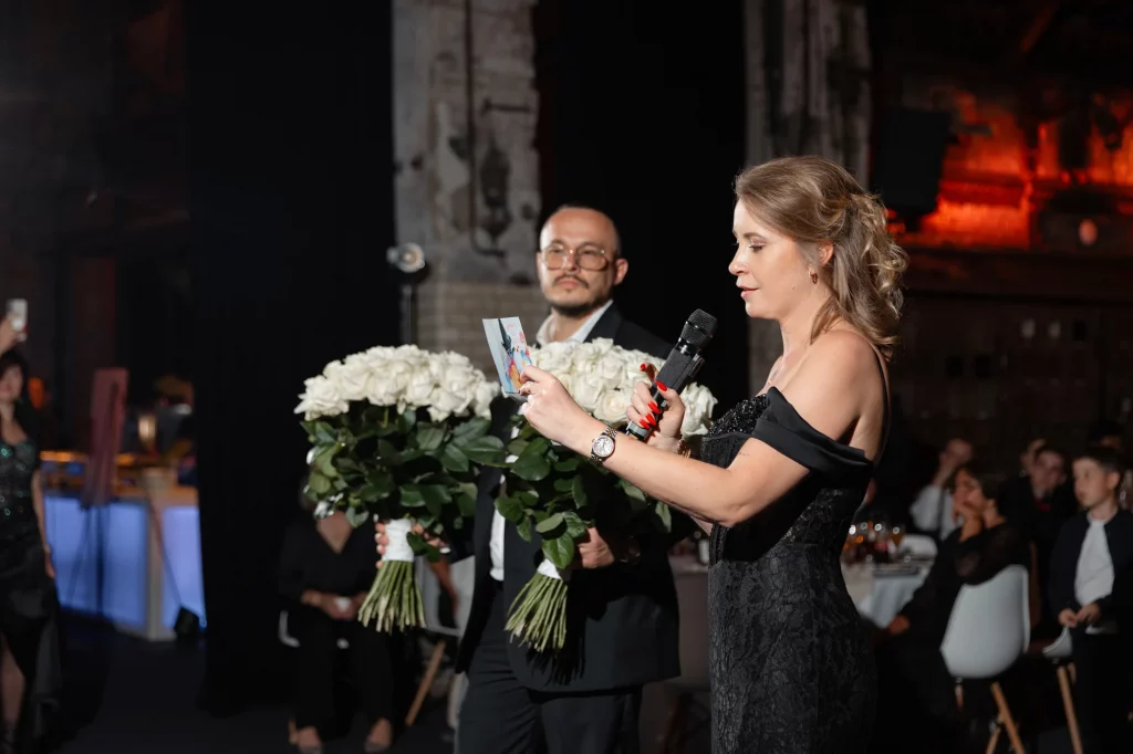 Frau liest mit Mikrofon vor, Mann mit Rosen