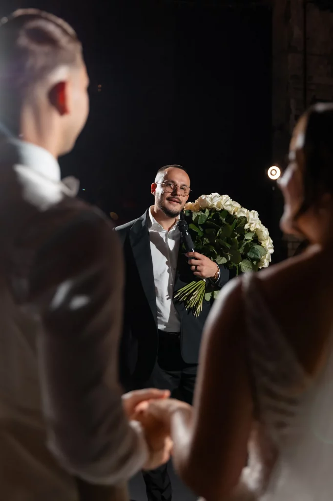 Mann mit Mikrofon und großem Rosenstrauß