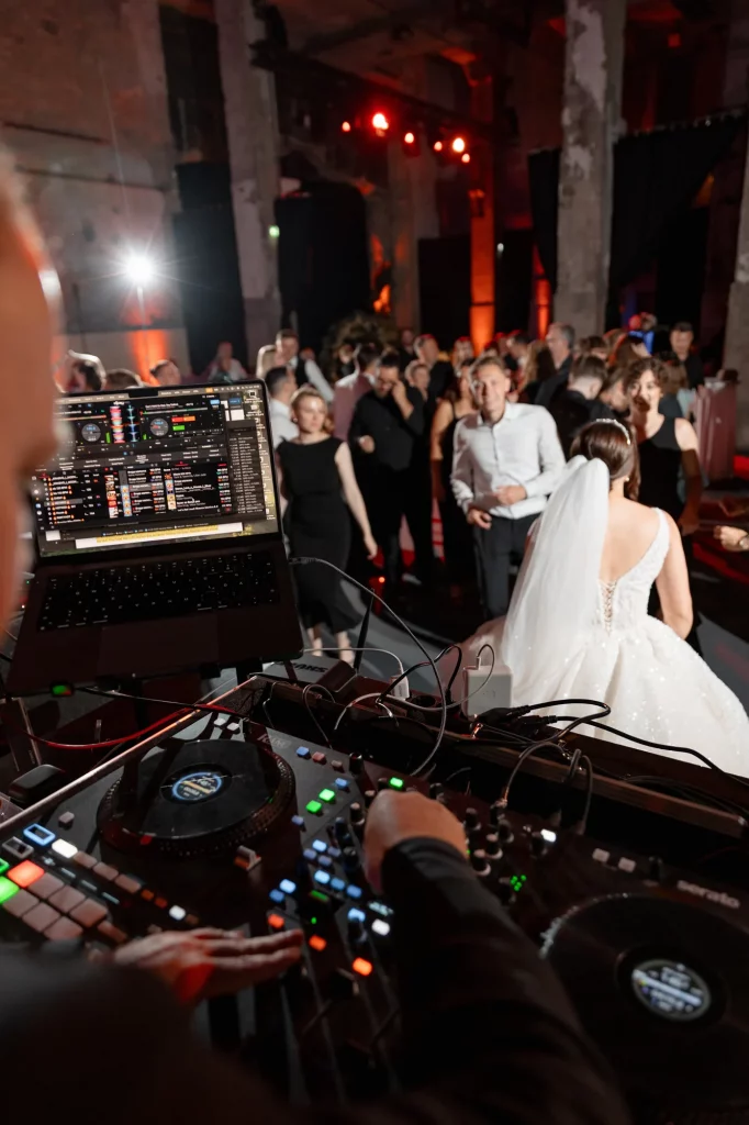 Braut tanzt mit Gästen vor DJ-Pult