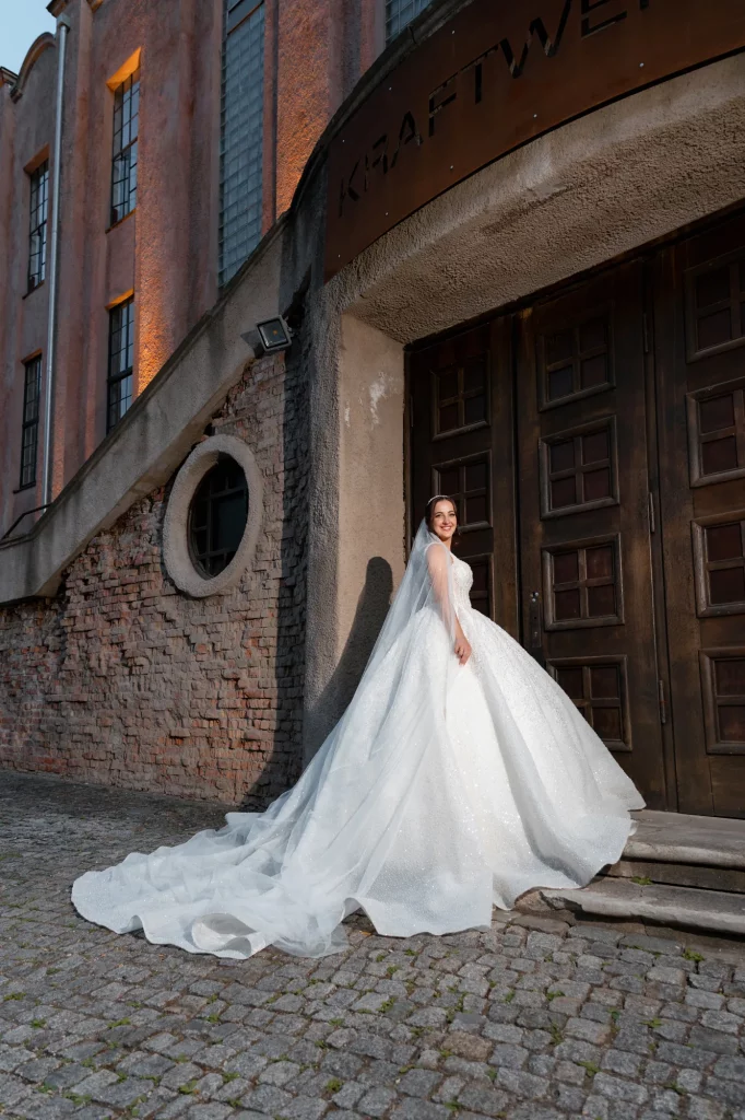 Braut in weißem Kleid vor altem Gebäude