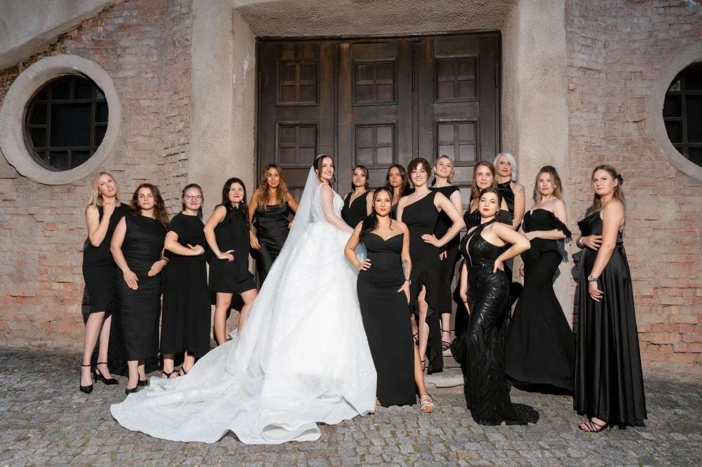 Braut mit Gruppe Frauen in schwarzen Kleidern vor Tür