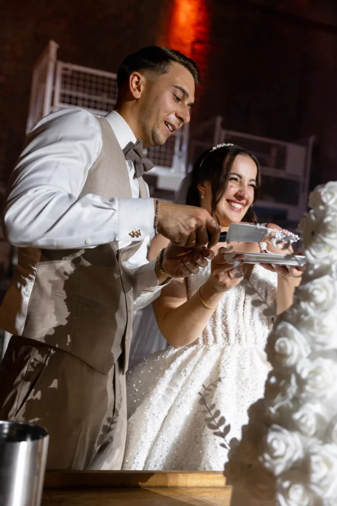 Brautpaar schneidet Hochzeitstorte lachend