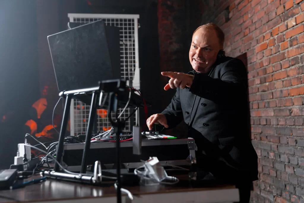 Mann mit Kopfhörern an DJ-Pult vor Backsteinwand