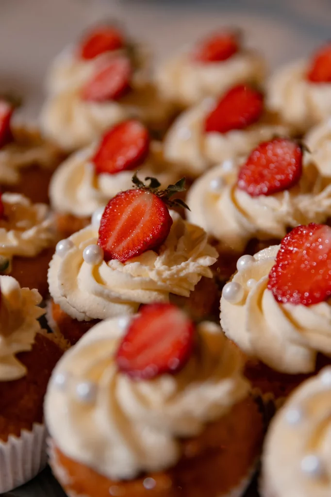Cupcakes mit Erdbeerscheiben und Sahnehaube