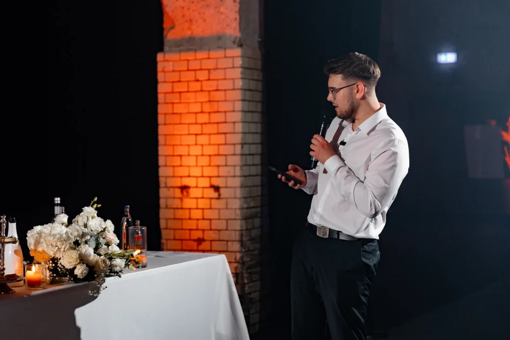 Mann mit Mikrofon bei Rede neben Blumendekoration