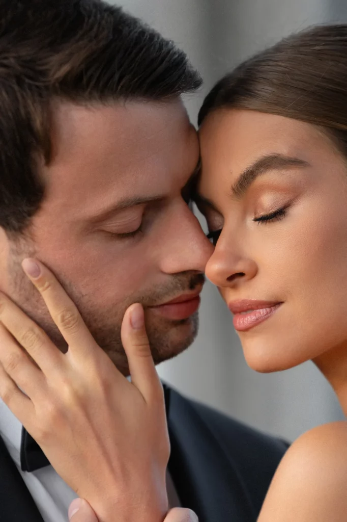 Zwei Personen mit geschlossenen Augen berühren sich, eine Hand liegt am Gesicht.