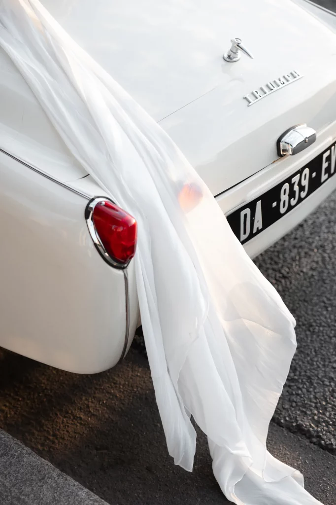 Weißer Stoff hängt über dem Heck eines weißen Autos mit rotem Rücklicht.
