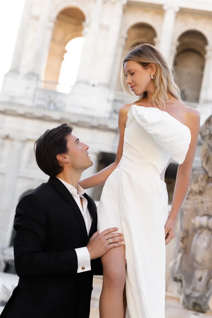 Zwei Personen in weißem Kleid und schwarzem Anzug vor hellen Bögen