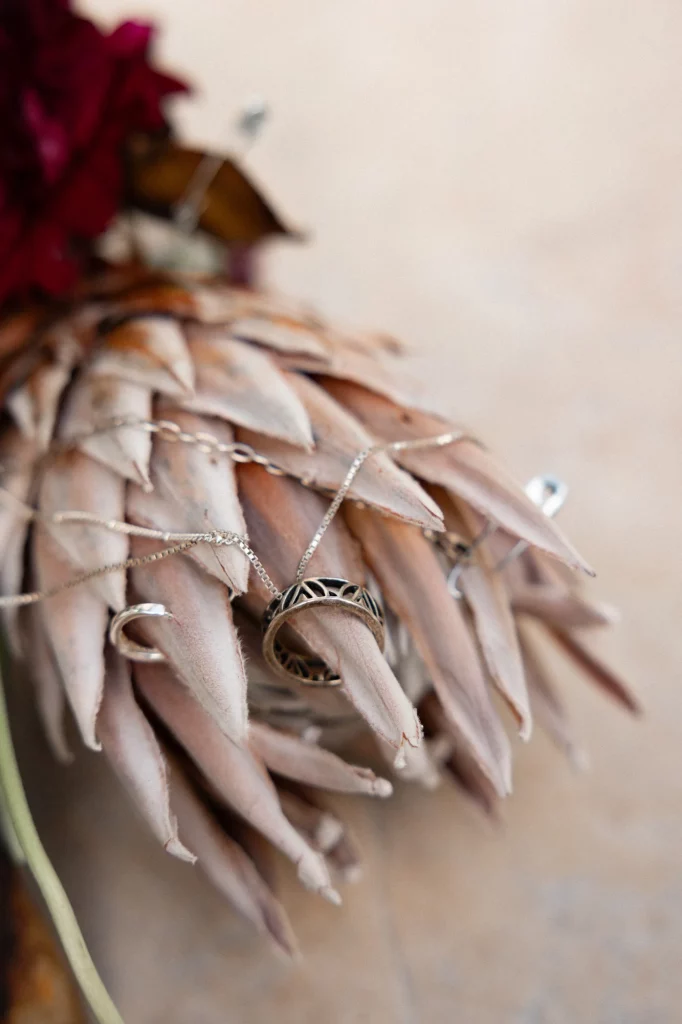 Verzierte Ringe und eine Kette liegen auf getrockneten Blättern.