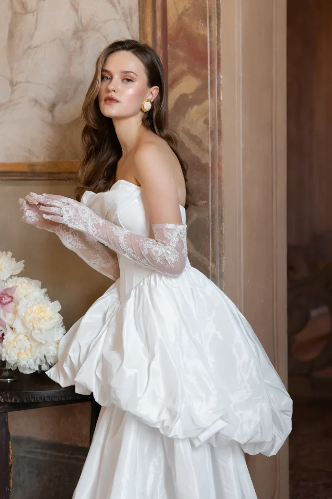 Braut im weißen Kleid mit Spitzenhandschuhen.