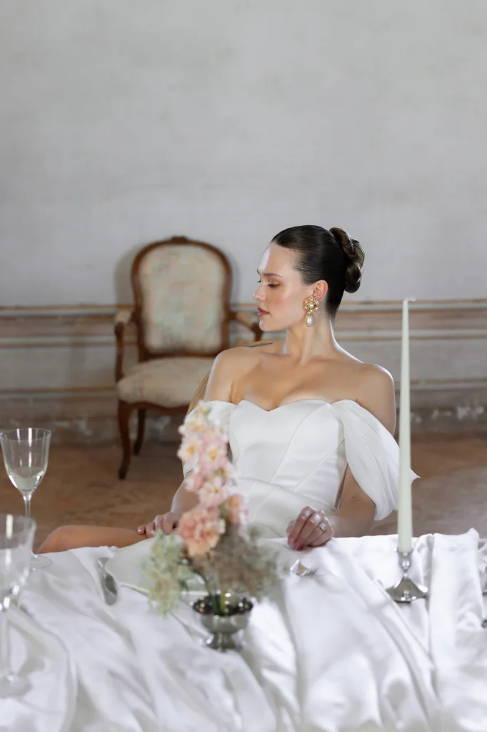 Braut im weißen Kleid am Tisch.
